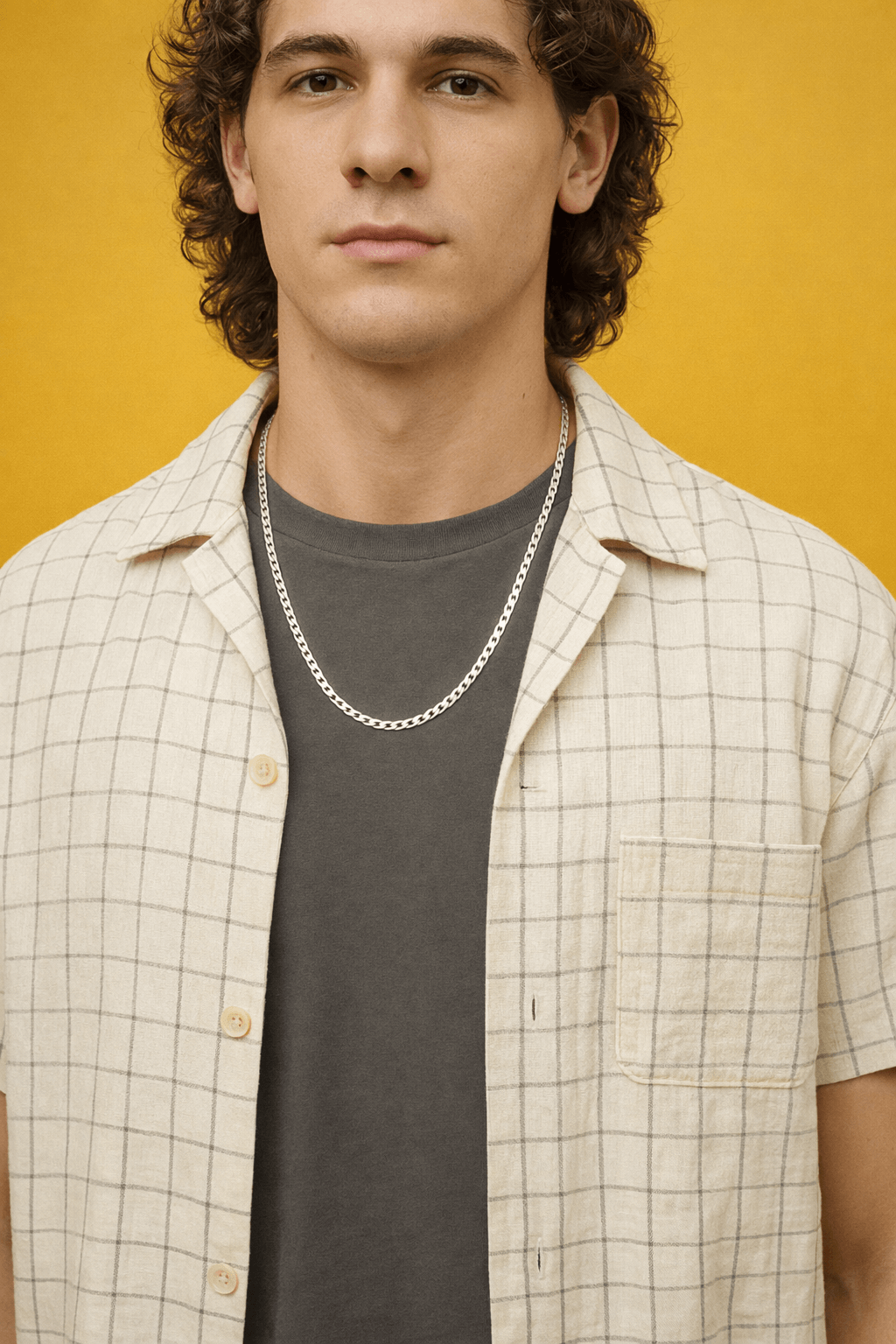 Man wearing a checkered shirt over a dark t-shirt with a yellow background