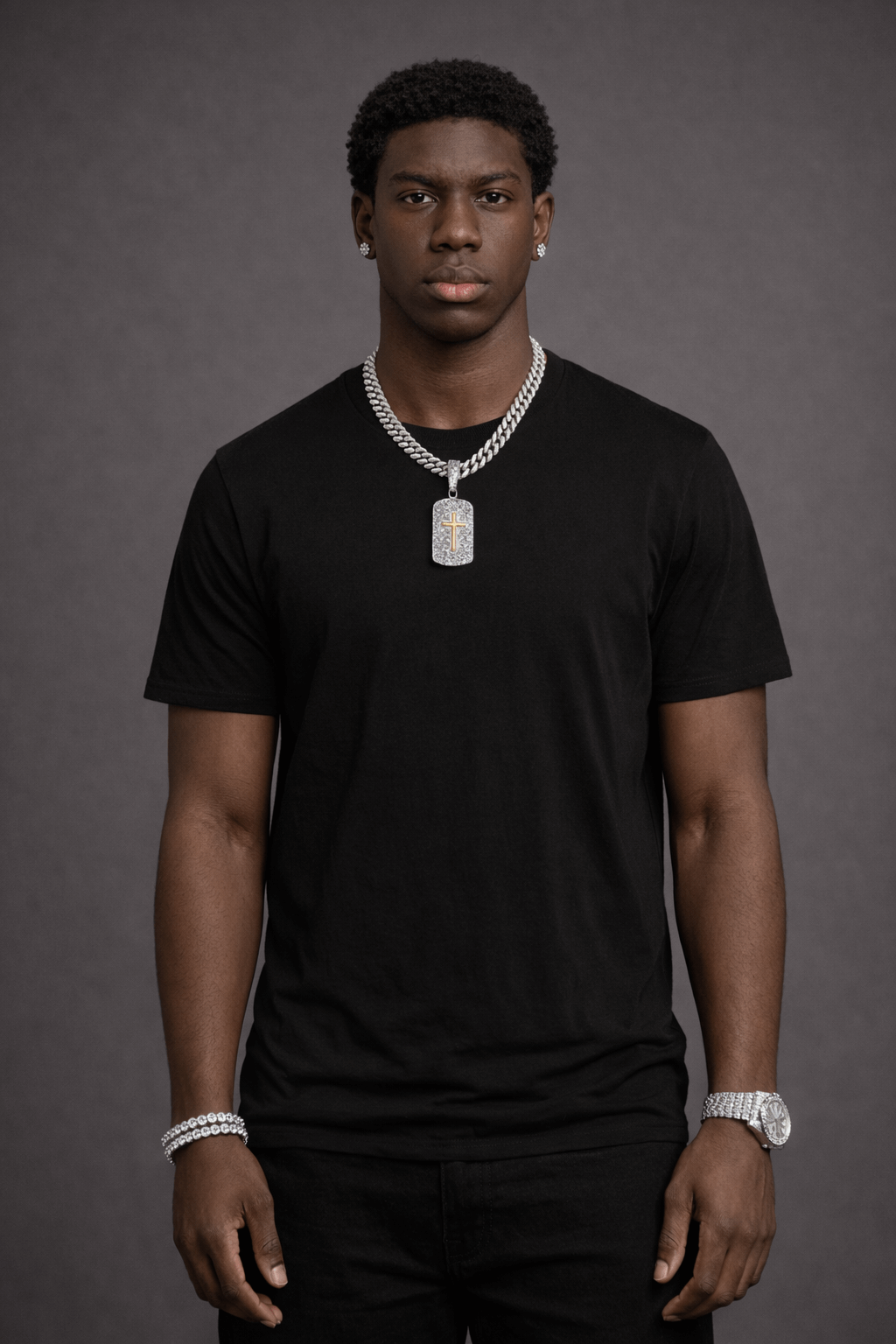 Man wearing a black t-shirt and silver jewelry against a gray background