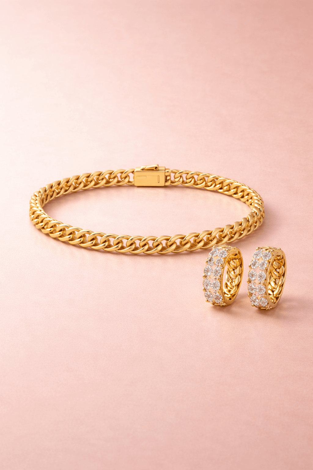 Gold bracelet and earrings on a pink background