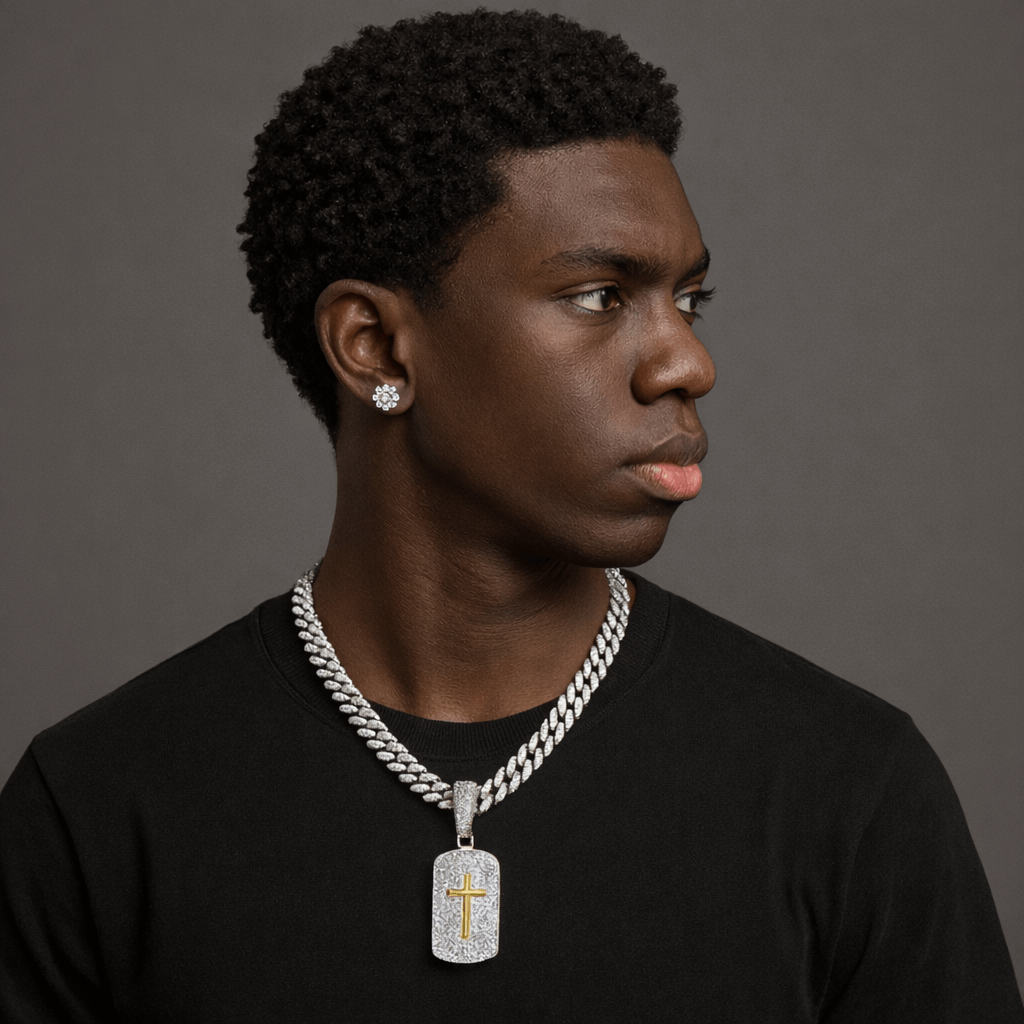 Man wearing a black shirt with a silver chain necklace and cross pendant against a gray background